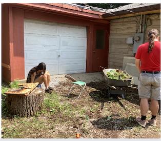 Two people perform gardening work in the former driveway of a suburban house.