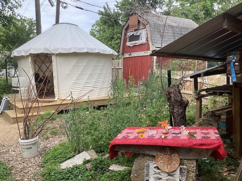 A yurt and two sheds surround a table set up as an altar.