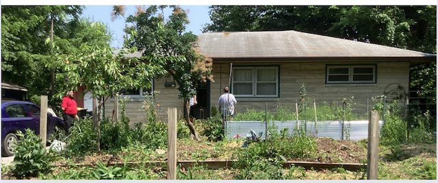 Limestone ranch house with garden and villagers in front.