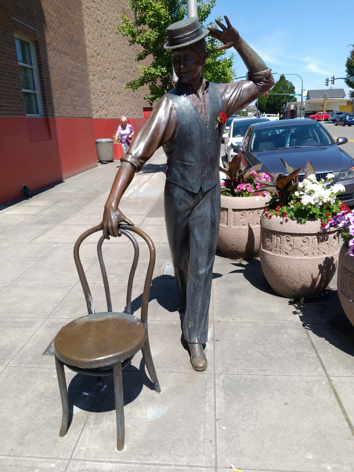 Life-size bronze statue of a dancing man in a hat.